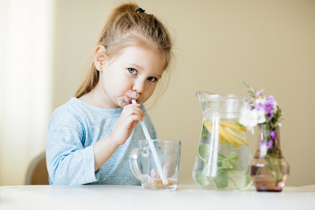 Photo cute little girl with glass of water in the kitchen