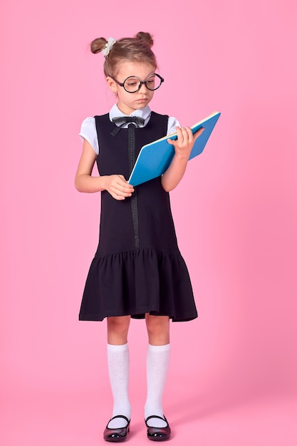 Cute little girl with glasses and books on pink space, space for text. Reading concept