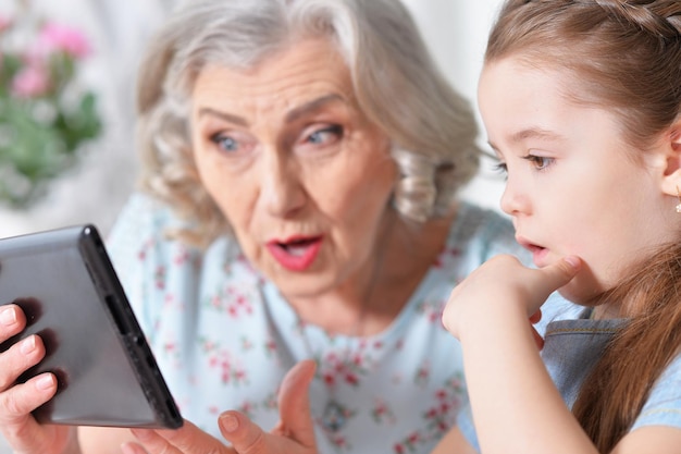 Милая маленькая девочка с бабушкой, глядя на планшет