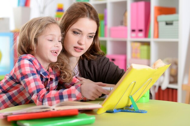 Cute little girl with her mother doing homework together in her room