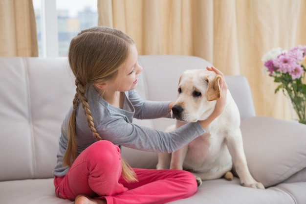 Cute little girl with her puppy on couch