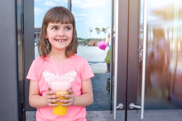 Cute little girl with orange juice outdoors