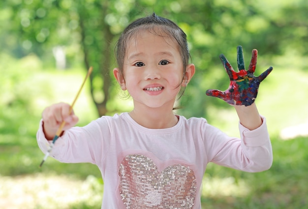 Cute little girl with painted hands in the park, Education art concept.