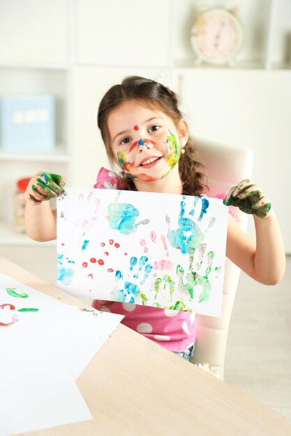 Photo cute little girl with picture on home interior background