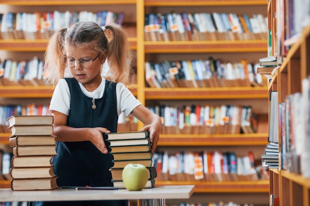 Photo cute little girl with pigtails is in the library