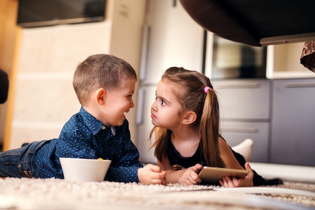 Cute little girl with ponytails looking strange at her brother.