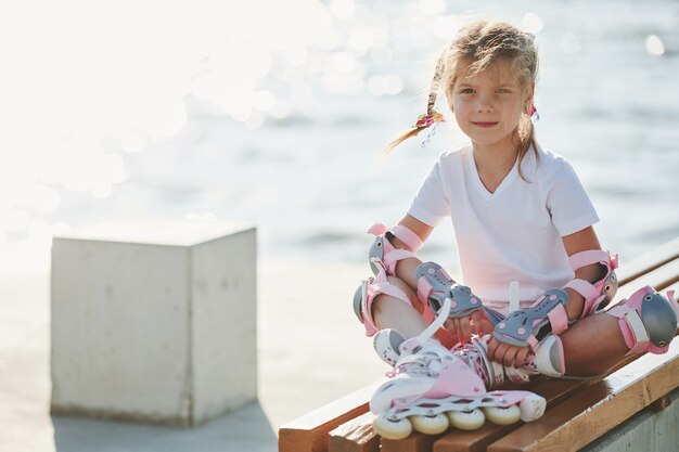 Cute little girl with roller skates outdoors near the lake