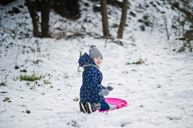 Cute little girl with saucer sleds outdoors on winter day.