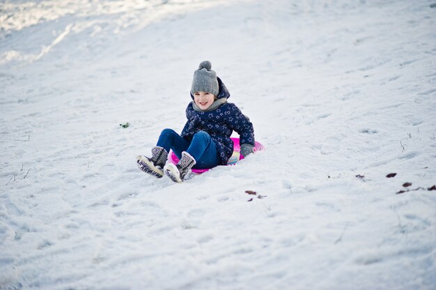 Cute little girl with saucer sleds outdoors on winter day.