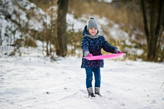 Cute little girl with saucer sleds outdoors on winter day.