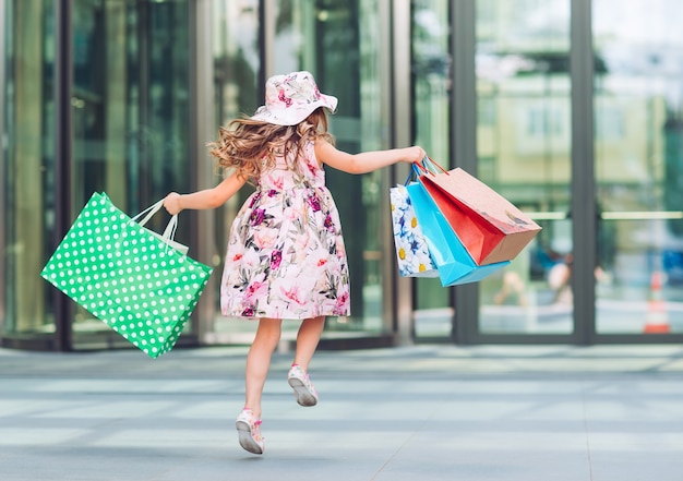 Bambina sveglia con i sacchetti della spesa