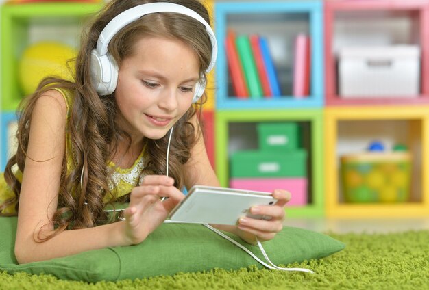 Photo cute little girl with smartphone and headphones