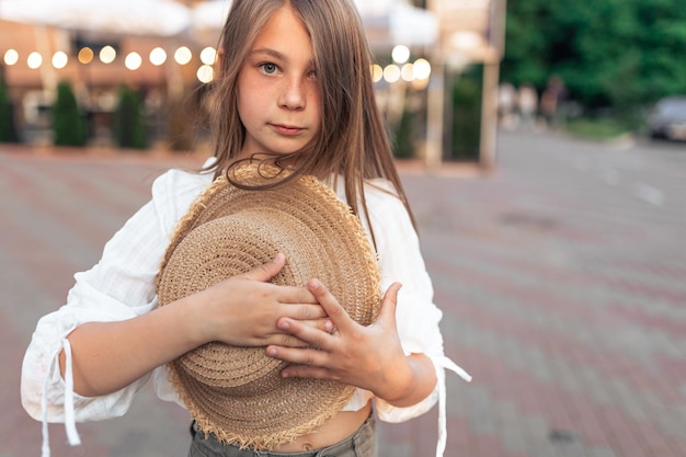 手に麦わら帽子をかぶったかわいい女の子は、夏と生活を楽しんでいます