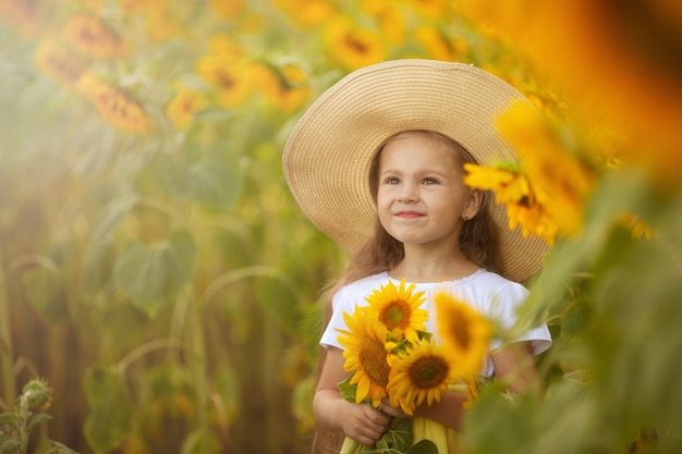 Милая маленькая девочка с подсолнухами на природе