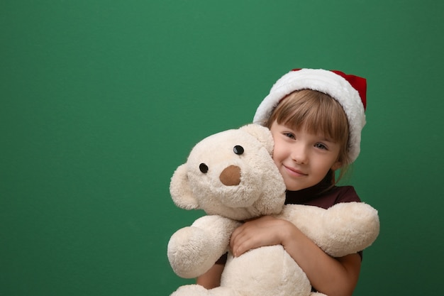 Cute little girl with toy on color background. Christmas concept