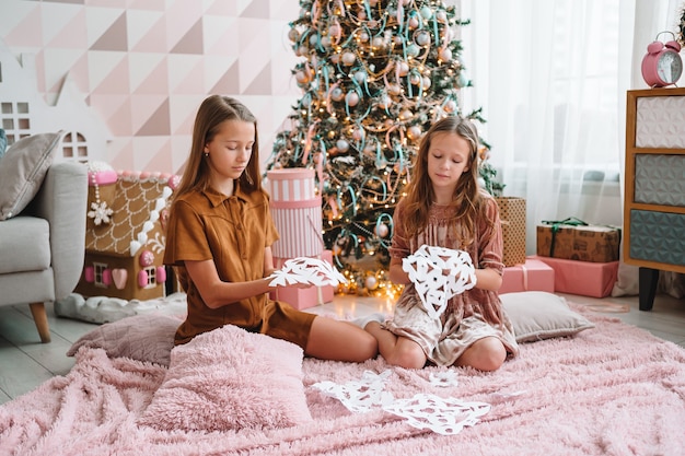 Cute little girls in living room making paper snow-flakes