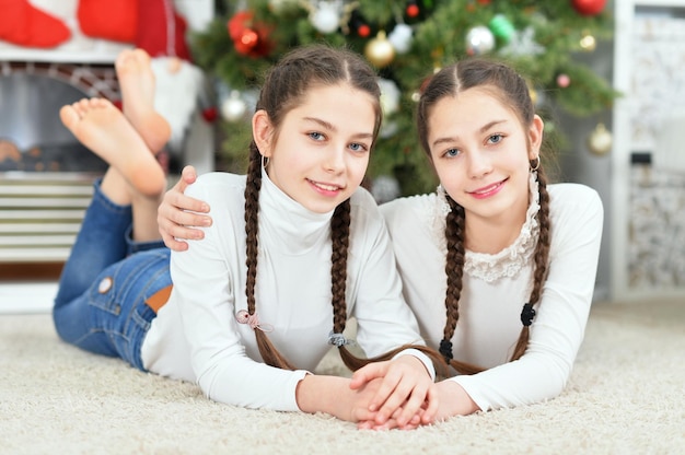 Cute little girls lying near decorated Christmas tree