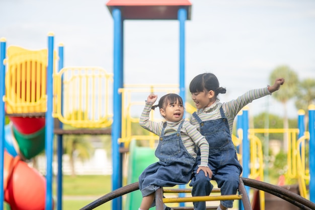 Cute little girls siblings having fun on playground outdoors on a sunny summer day. active sport leisure for kids