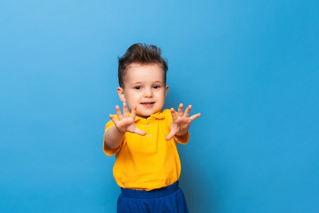 Cute little grimaces stands on a blue background. Funny kid