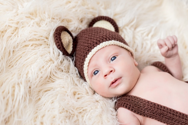 Cute little happy baby lies in a bear costume on a white. newborn in a hat with ears on a white