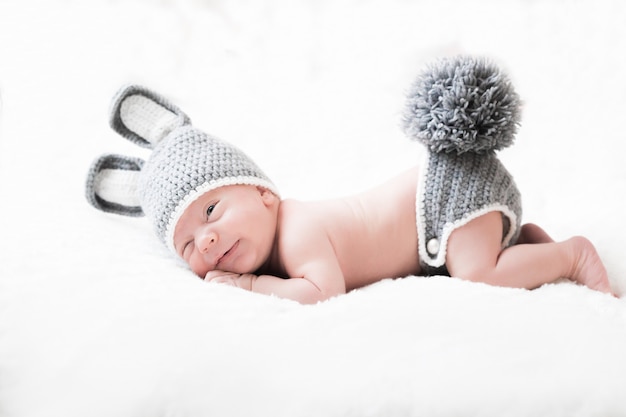 Cute little happy baby lies in a hare costume. newborn in a hat with ears