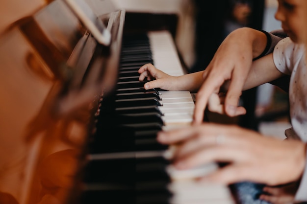 Cute little happy child girl playing piano in a light room Selective focus noise effect