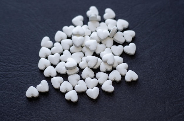 cute little heart shaped pills on black structured background medicine concept heart diseases