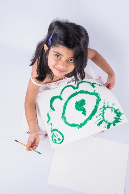 Cute little Indian or Asian Girl enjoying Painting at home with paper, water colour and art brush. Selective focus