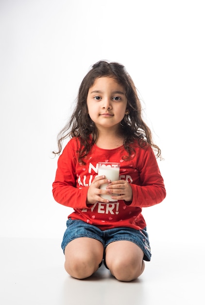 Cute little Indian asian girl holding a glass full of Milk - healthy eating concept