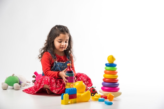 Cute Little Indian Asian girl playing with colourful block toys over white background