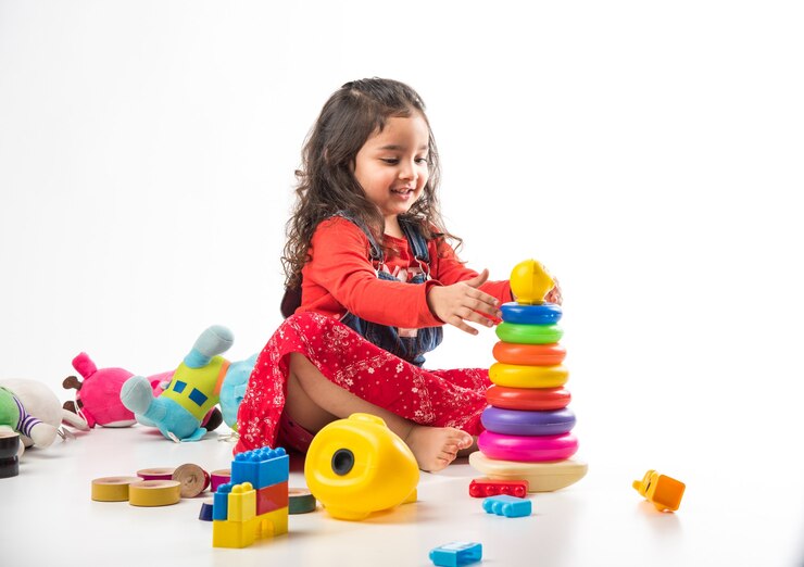 Cute Little Indian Asian girl playing with colourful block toys over white background