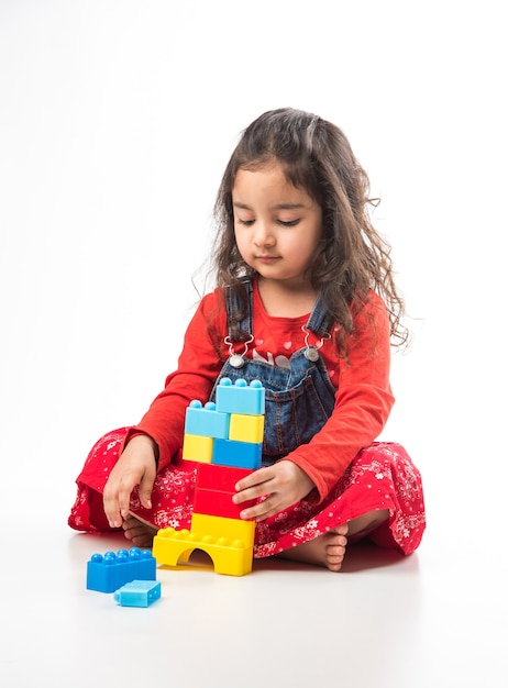 Cute Little Indian Asian girl playing with colourful block toys over white background