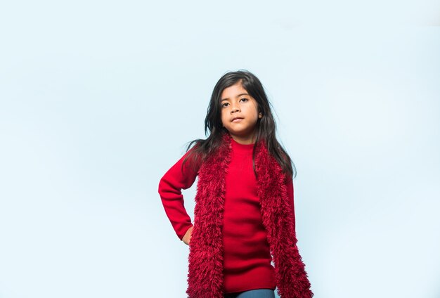 Cute Little Indian Asian Girl wearing Santa Hat celebrating christmas while standing isolated over plain background