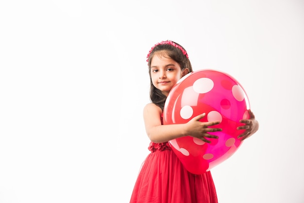 Cute little indian or asian girl with colourful balloons or gubbare in Hindi, over white or red background