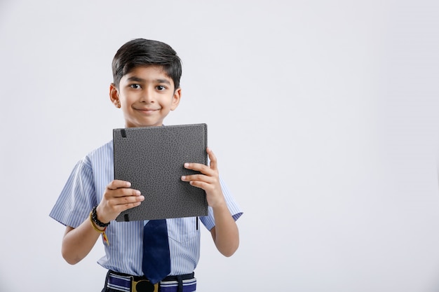 Cute little Indian / Asian school boy showing note book over white background