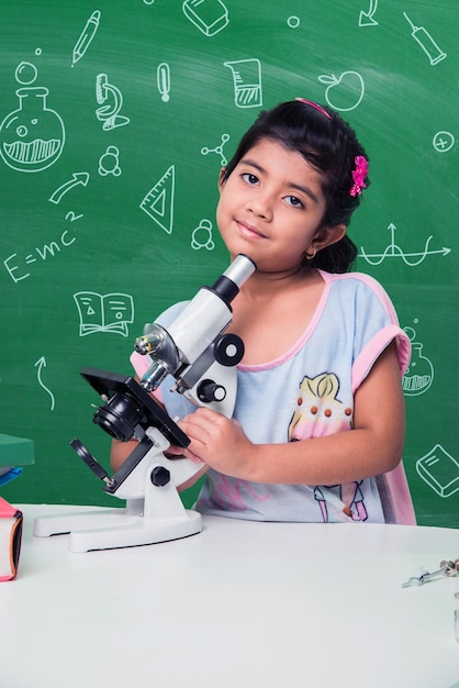 실험실에서 과학을 실험하거나 연구하는 귀여운 인도 아시아 여학생, 교육용 낙서가 있는 녹색 칠판 배경
