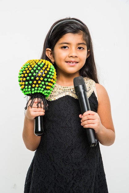 Милая маленькая индийская девочка поет в микрофон, изолированные на белом фоне