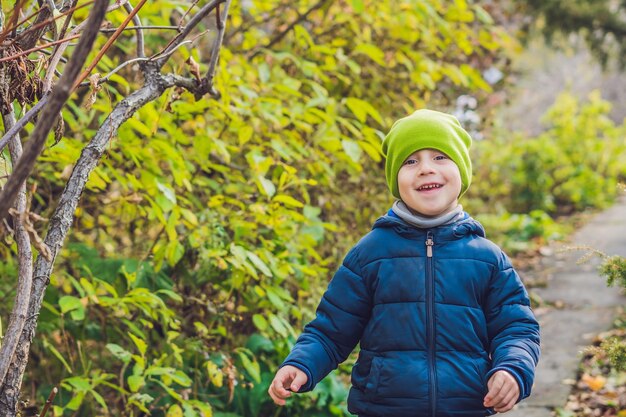 秋の日を楽しんでいるかわいい男の子。カラフルな秋の服を着た未就学児が登ることを学び、暖かい晴れた日に庭や公園で楽しんでいます