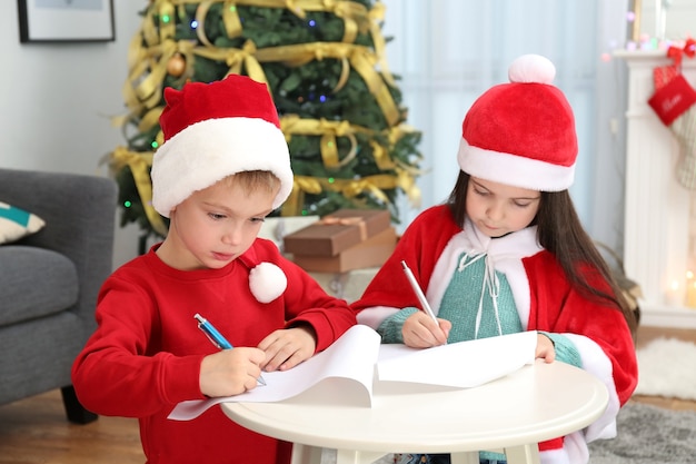 Cute little kids writing letter to Santa Claus at table