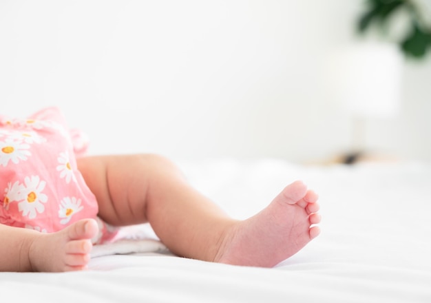 Cute little newborn baby feet on bed at home