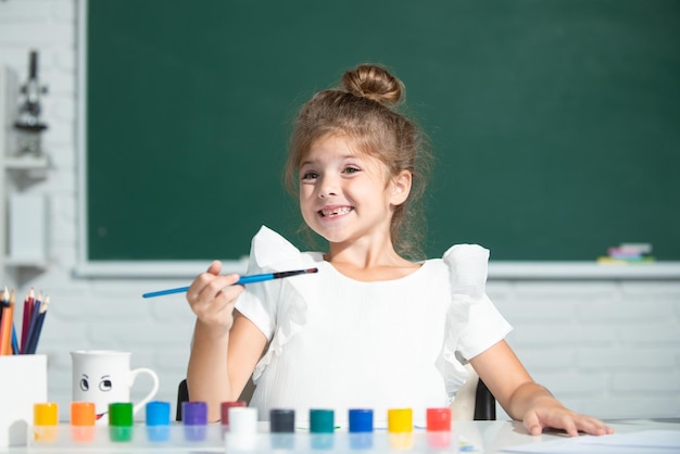 Cute little preschooler child girl drawing at school Child girl painting on elementary school Funny kids emotions