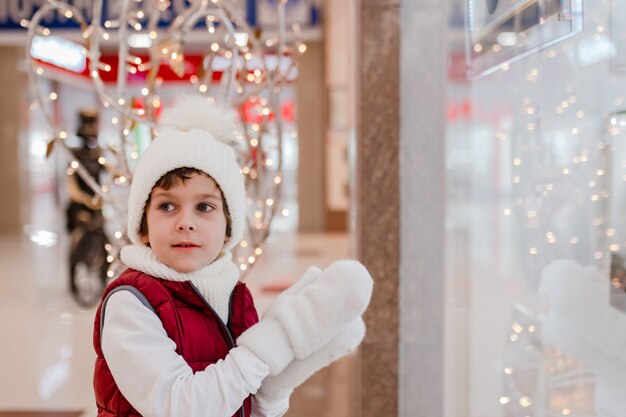 Cute little school kid boy on christmas market holidays christmas childhood and people concept