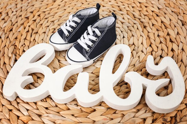 Cute little shoes and word baby on wicker mat