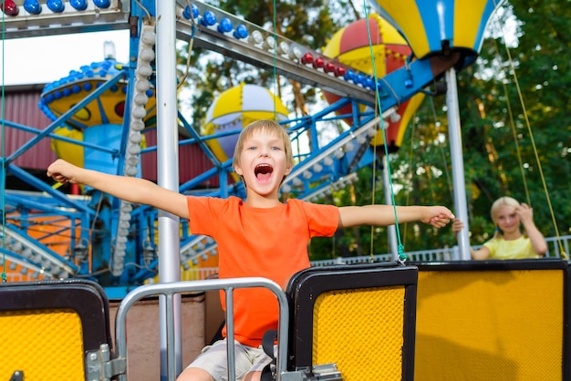 Cute little smiling boy riding a Carnival Carousel at an summer park