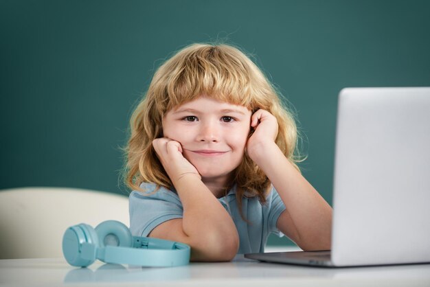 Cute little student boy using laptop computer in school\
class