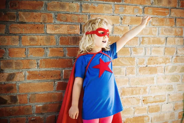 Ragazza carina super eroe contro il muro di mattoni. concetto di supereroe.