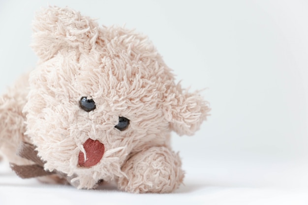 Cute little teddy bear lay down on the bed.