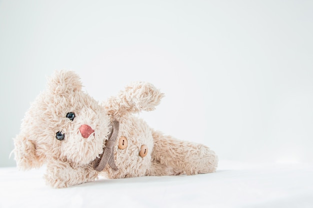 Cute little teddy bear lay down on the bed.