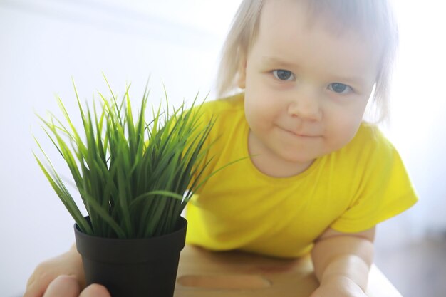 家で植えられた花とポットを持って楽しんでいるかわいい幼児の女の子。花と自然のケアのコンセプト。子供と家族の幸せな子供時代。