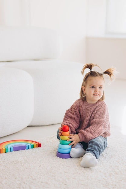 Cute little toddler girl playing at home with eco wooden toys Happy child cutting vegetables and fruits with toy knife The child playing educational games